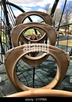 A little girl climbs on playground equipment In Bentonville, Arkansas. Stock Photo