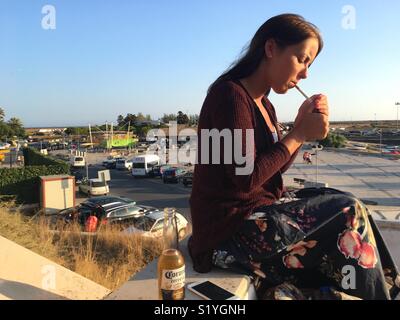 Young woman lighting a cigarette. Alvor, Portugal, summer 2017 Stock Photo