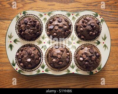Banana chocolate muffins baked in a floral ceramic pan on a wooden surface Stock Photo