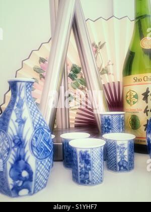 Porcelain sake cups and serving containers with bottle of sake close up still life Stock Photo