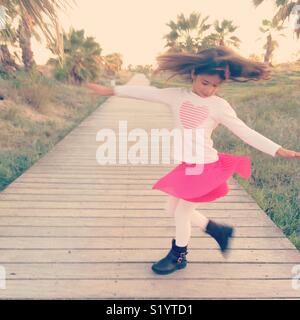 Girl dancing in a pink skirt, turning next to palmtrees Stock Photo