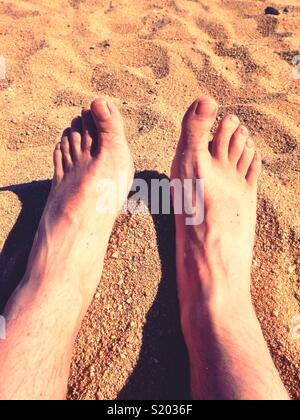 Male feet on a sandy beach. Stock Photo