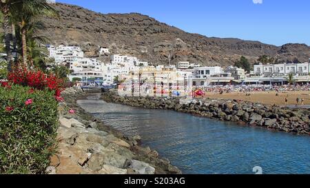 View to over small river to the promenade and beach of Puerto de Mogan, in the south west of the spanish canary island Gran Canaria Stock Photo