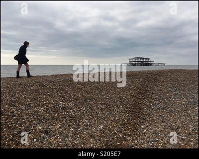 Woman walking alone on Brighton beach, England, April 2018 Stock Photo