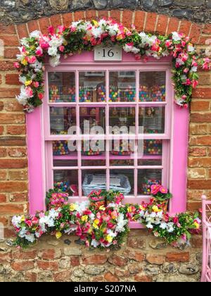 The pretty pink window of a quaint cottage decorated with colourful flowers Stock Photo