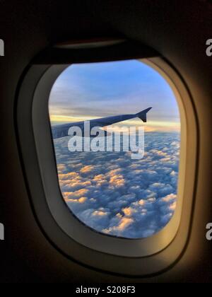 Sunset view out of the passenger window of a British Airway Airbus somewhere over Europe. Clouds and the aircraft wing complete the view. Photo Credit - © COLIN HOSKINS. Stock Photo