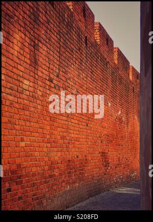 View down an alley way - a tall brick wall provides security and separation. An image with multiple uses and connotations. Photo Credit - © COLIN HOSKINS. Stock Photo