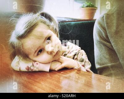 Young girl resting head o. Arm on a restaurant table looking sad Stock Photo