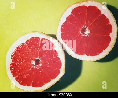 Juicy, Ruby Red grapefruit cut in half on a bright green cutting board Stock Photo