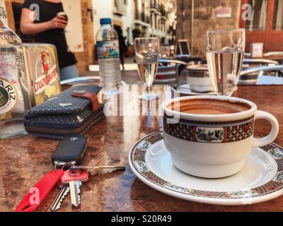 Cup of coffee, cafe con leche, with purse and bunch of keys, on a table at an outdoor cafe, Spain Stock Photo
