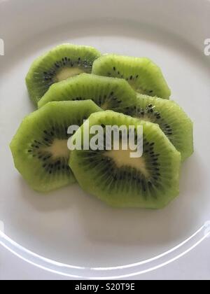 Kiwi slices on white plate Stock Photo