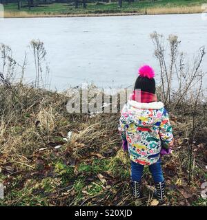 Child looking out over frozen lake Stock Photo