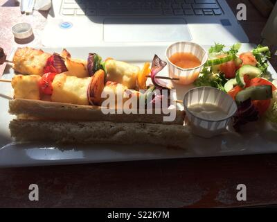 Plate of halloumi, sauce dips and roasted vegetables by laptop Stock Photo