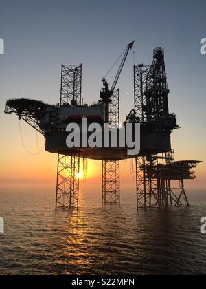 Sun setting behind drilling rig. Stock Photo