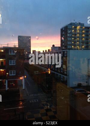 Raindrops against a window in East London at sunset Stock Photo
