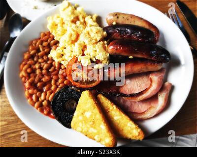 Full English breakfast with sausages, egg, bacon, beans, hash browns, mushroom and tomato. Stock Photo