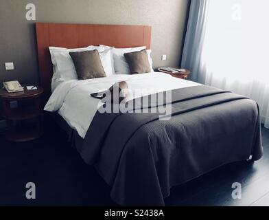 Woman’s handbag lying on a hotel bed Stock Photo