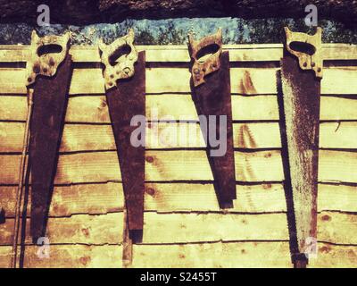 Old hand saws hanging on a garden fence, Medstead, Hampshire, United Kingdom. Stock Photo