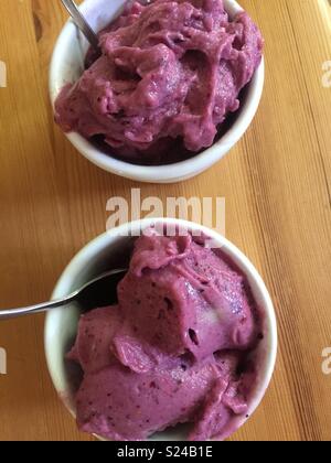 Banana ice cream or ‘nice cream’ with mixed berries served in white ramekins.