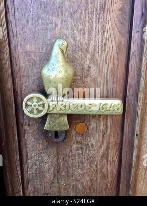 Brass door handle with dove and the word ‘Frieden’ -‘Peace’ on the entrance door to Osnabruck town hall. Stock Photo