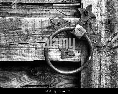Old metal door knocker handle on barn door in monochrome. Stock Photo