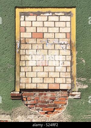 A bricked up window in a green wall Stock Photo