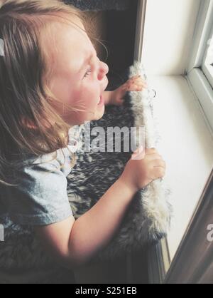 Toddler girl having a crying and having a temper tantrum at a window Stock Photo