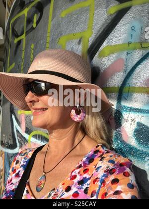 Woman leaning against a graffiti wall. Stock Photo