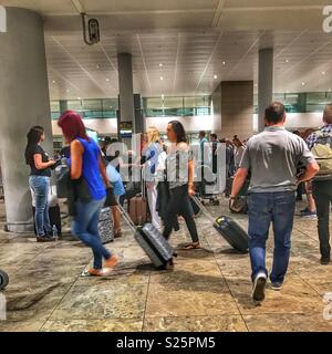 Travellers arriving in Alicante, collecting luggage from the baggage claim area of El Altea Airport, Spain Stock Photo