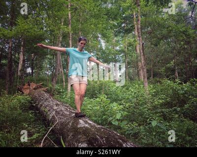 Woman balances on log in forest Stock Photo