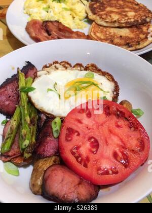 Breakfast of beef tenderloin medallions, asparagus, fried and scrambled egg, pancakes, and tomato Stock Photo