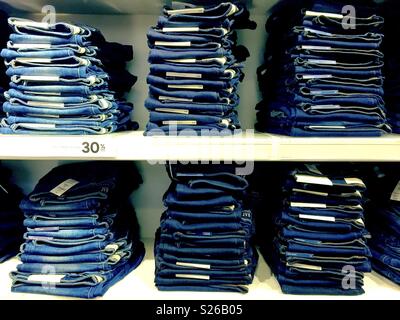 Stacks of denim jeans on display for sale in a clothes shop. Stock Photo