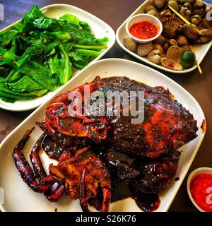 Black pepper crab, clams with chilli sauce and gai lan with garlic at East Coast Lagoon Food Village, a hawker food market in Singapore Stock Photo