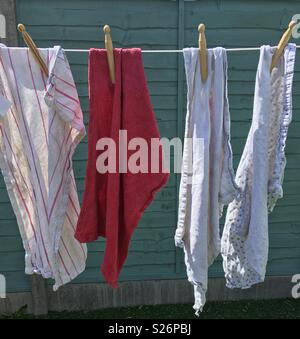 Old tea towels on a washing line held by wooden dolly pegs Stock Photo