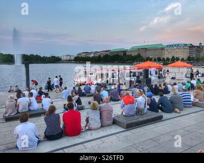 Spending a relaxing evening outdoors on the steps by the Alster in downtown Hamburg, Germany. Stock Photo