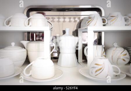 ceramic cups, teapots and coffee pots on a shelf Stock Photo