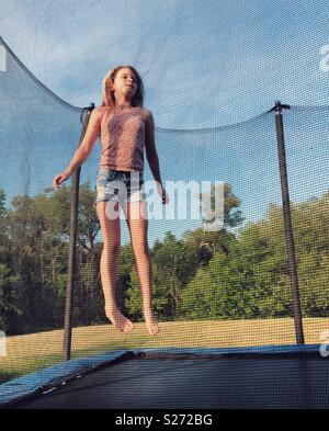 Girl Kid Jumping On Trampoline With Autumn Leaves. Bright Yellow Orange 