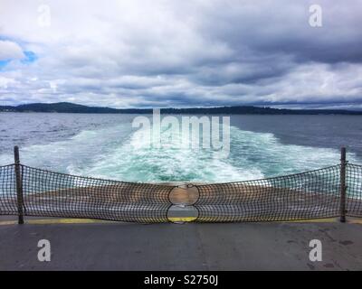 Ferry boat wake with Bainbridge Island as the horizon line on a cloudy day, Puget Sound, Washington State, USA. Stock Photo