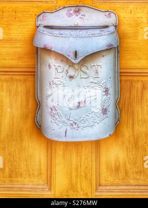 Old post box hanging on yellow door Stock Photo