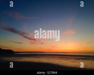 As the setting sun dips below the horizon over Southampton, the sky lights up with a glorious orange hue. Photographed from Ryde on the Isle of Wight, UK. Stock Photo