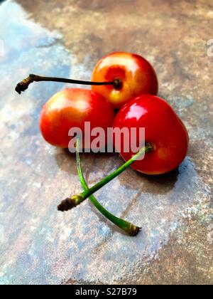 Three cherries on a wet surface Stock Photo