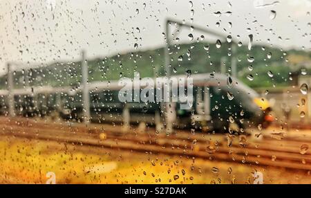 Raindrops on the window of an express train as it passes another train Stock Photo