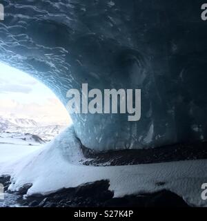 Curved blue ice wall at the entrance of an ice cave in Iceland Stock Photo