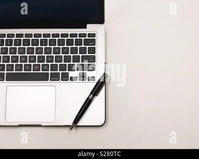 Top view of a laptop with a pen on working table. Stock Photo