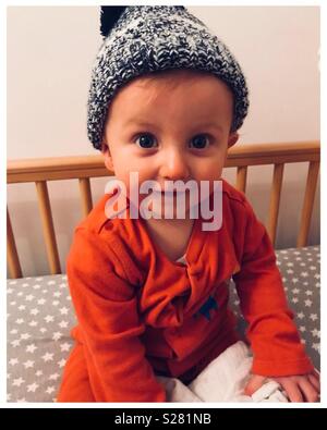 Little boy wearing wooly that sitting in cot Stock Photo