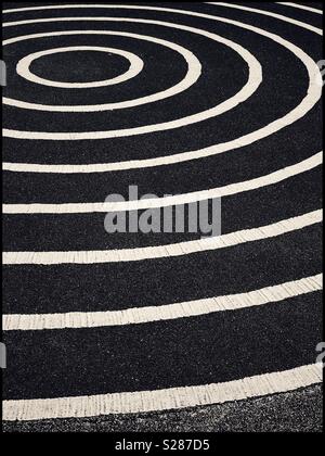 A graphic, monochrome image of concentric circles, painted onto a large area of tarmac (asphalt). An image with multiple potential uses. Photo Credit - © COLIN HOSKINS. Stock Photo