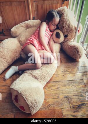 girl cuddling with giant teddy bear