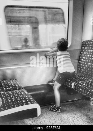 A boy looking through the window at the passing train Stock Photo