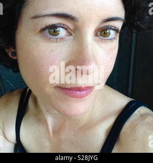Woman with hazel eyes and dark brown hair wearing pink lipstick Stock Photo