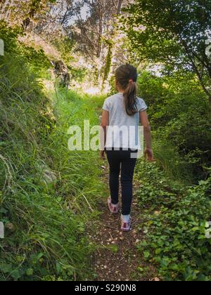 Small girl walking on the forest path Stock Photo